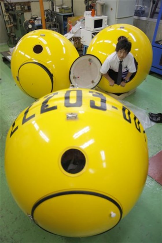 A Cosmo Power Co. employee crawls out from a "Noah" survival shelter, at the company's factory in Hiratsuka, west of Tokyo, Friday.